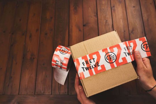 Diseño retro en blanco y naranja sobre cinta personalizada en una caja kraft.