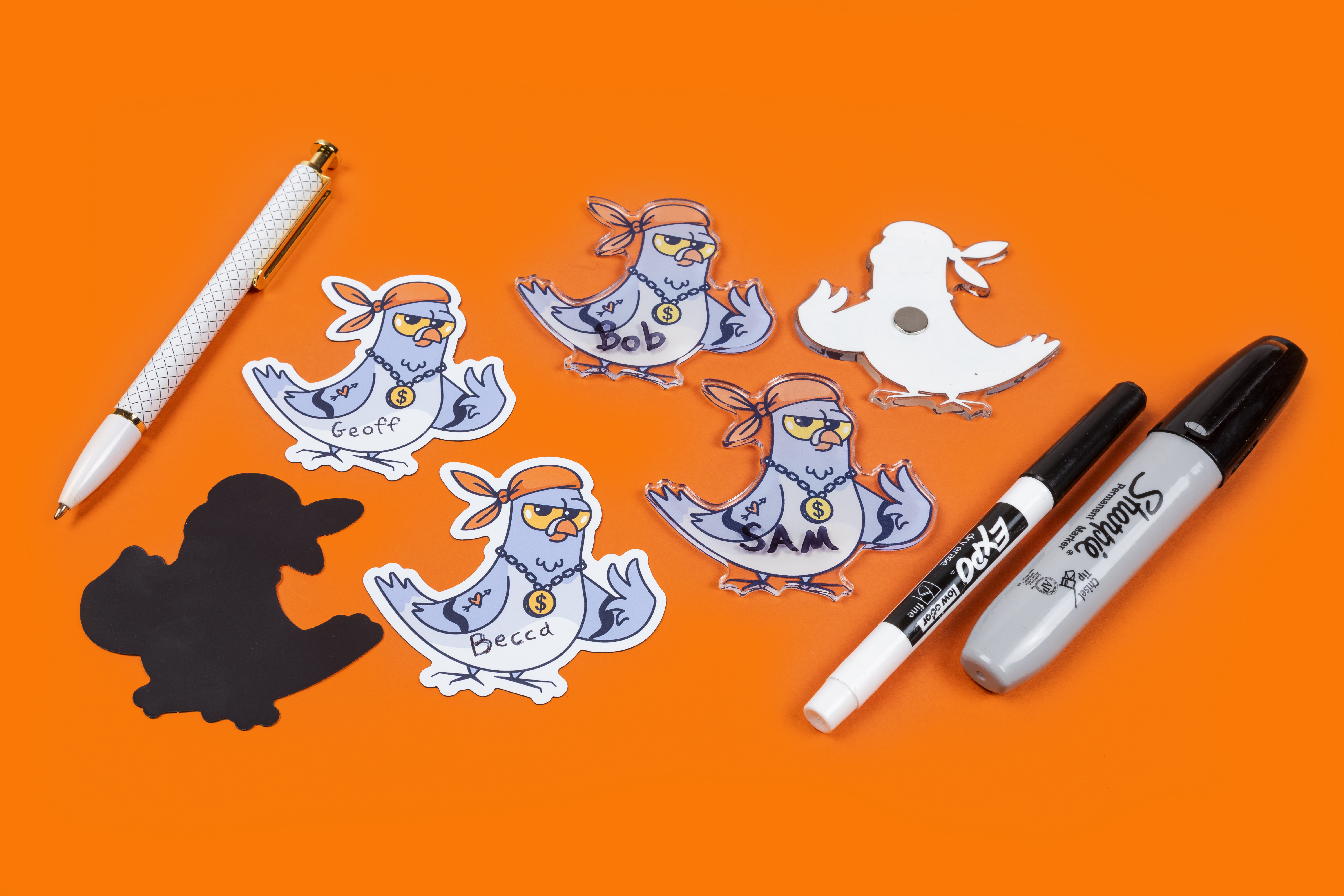 exemplos de ímanes standard e ímanes acrílicos escritos com caneta e marcador sobre um fundo laranja