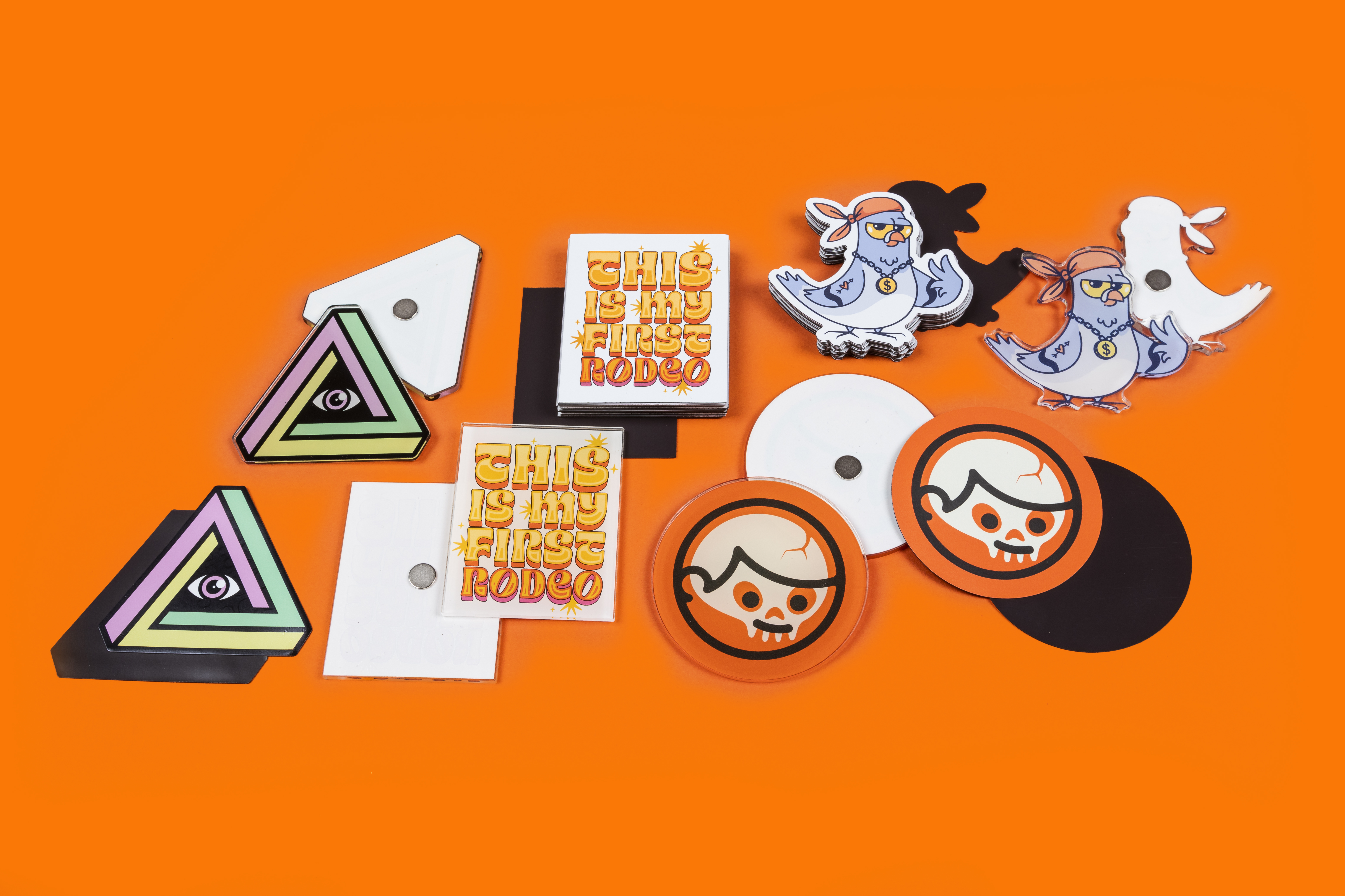 Image of triangular, rectangular, round, and die cut shaped acrylic and standard magnets on an orange background