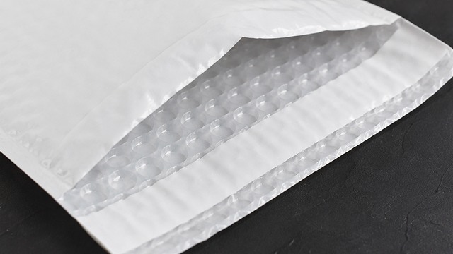 Close-up of an open white bubble mailer, revealing the clear plastic bubble wrap padding lining the interior.